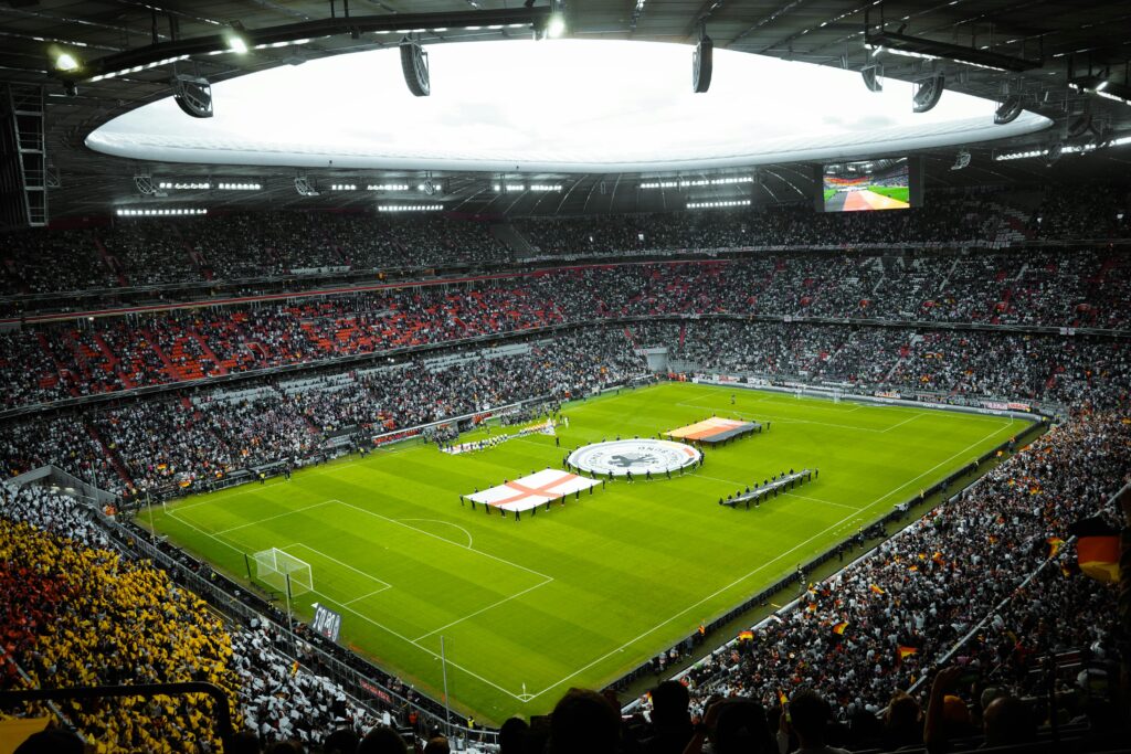 A vibrant soccer stadium filled with fans watching a game, flags displayed on the field.