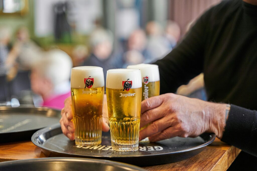 Close-up of fresh beers being served on a tray in a bustling pub.