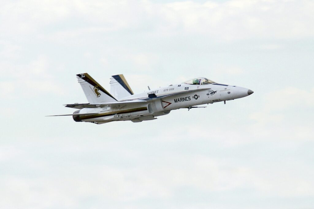 High-speed US Marines Hornet jet soaring through a clear sky, showcasing military might.