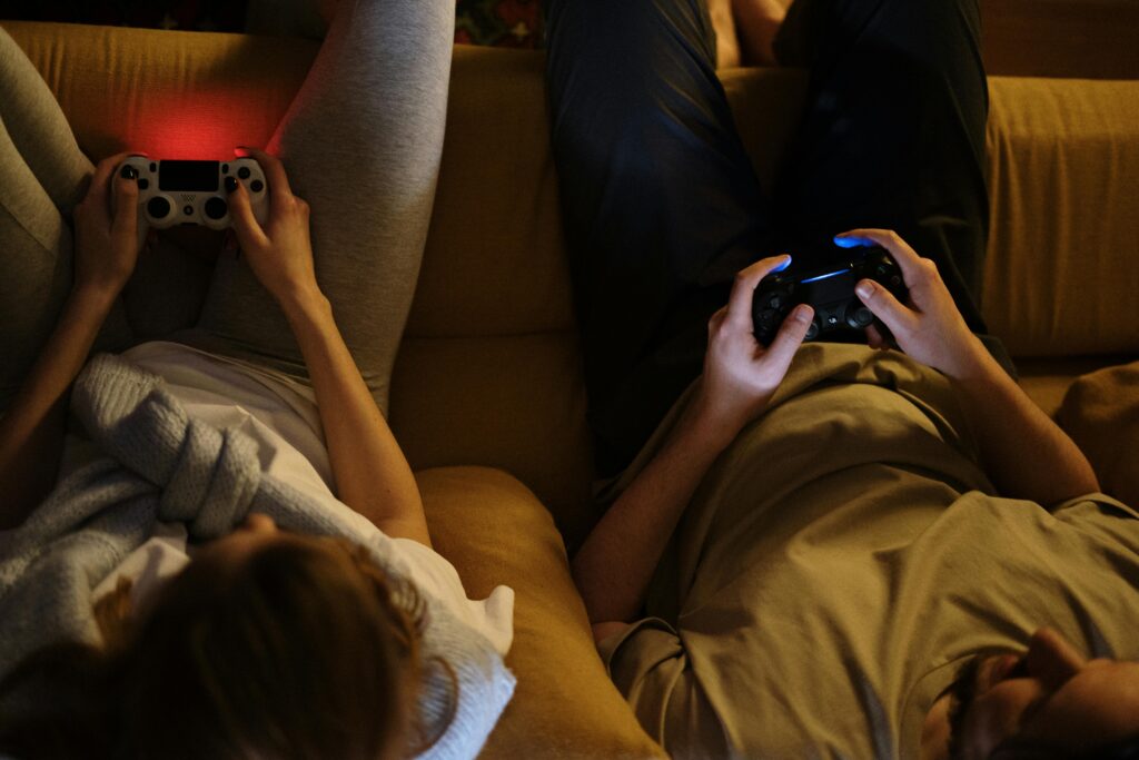 A couple enjoying an evening playing video games together on the sofa in cozy home lighting.
