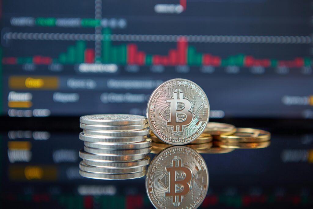 Stack of Bitcoin coins in front of a stock market graph, reflecting cryptocurrency trends.