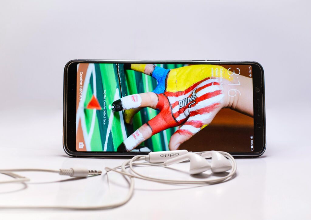 Smartphone displayed with wired earphones, featuring colorful screen on a white background.