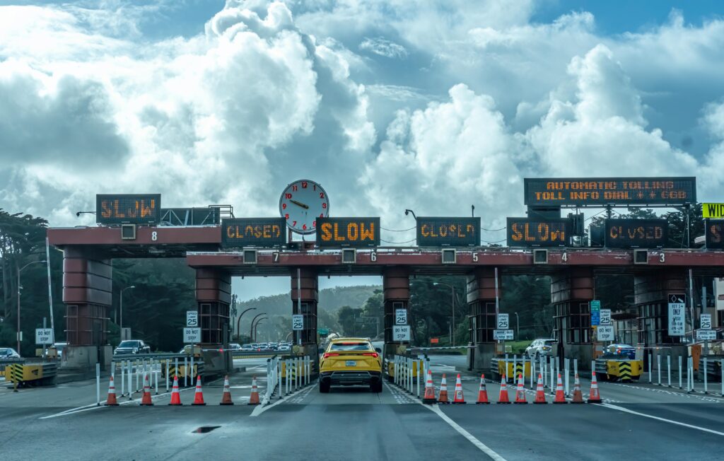 View of vehicles approaching the toll plaza at Golden Gate Bridge in San Francisco under a cloudy sky.