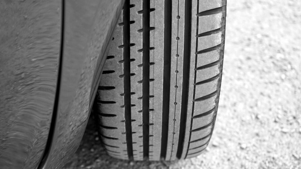 Detailed view of vehicle tire on a gravel surface, showcasing tread pattern.