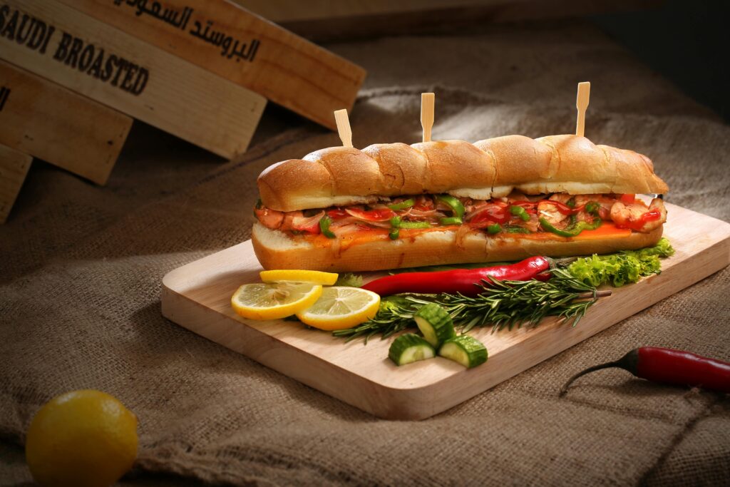 Mouth-watering sandwich with vegetables and sausage on wooden board, perfect for a delicious meal.