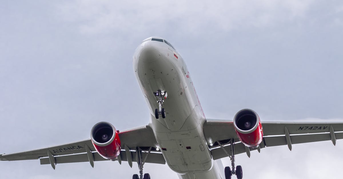 Airplane in-flight with visible landing gear against a cloudy backdrop in Bogotá, Colombia.