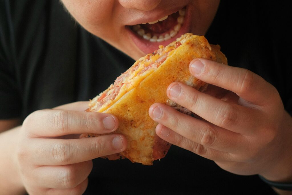 A person indulges in a delicious sandwich, highlighting flavors and texture.