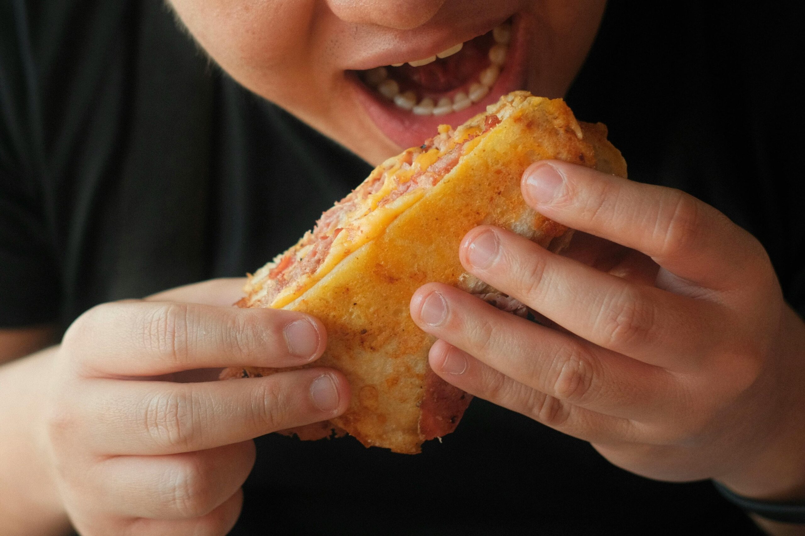 A person indulges in a delicious sandwich, highlighting flavors and texture.