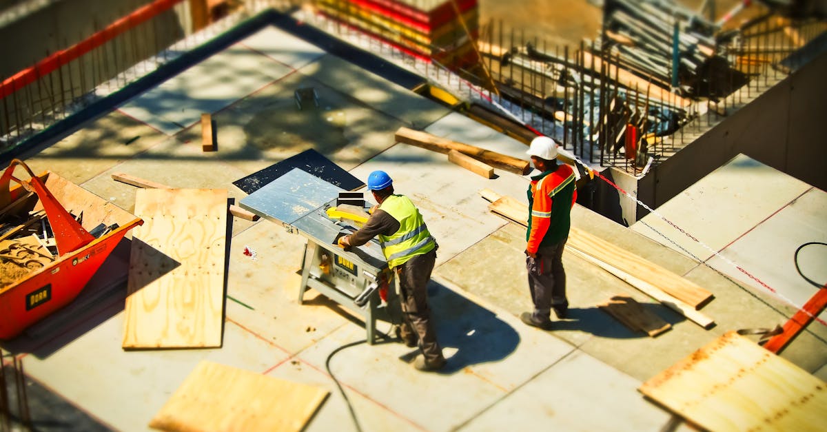 Construction workers engaging in tasks at an outdoor building site with safety hats and equipment.