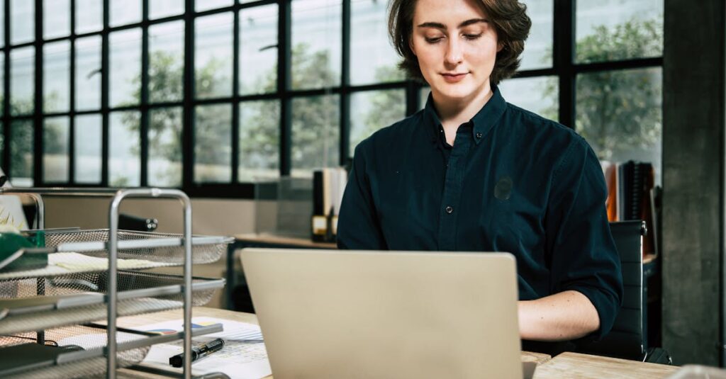 Professional woman using laptop in a stylish office environment, focused on work.