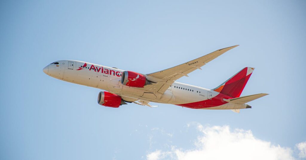 Avianca passenger jet flying under a clear blue sky, showcasing flight travel.