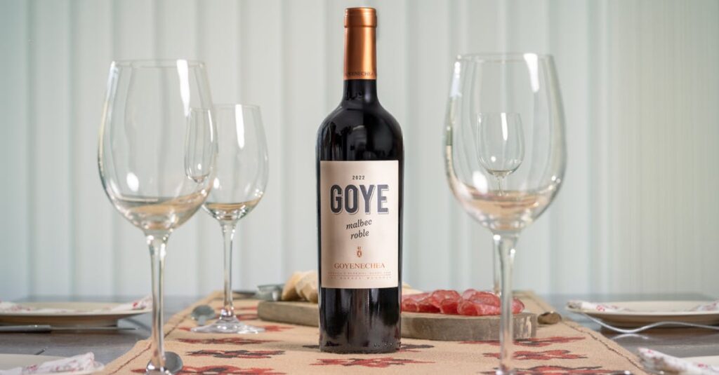 A bottle of Goye Goyenechea Malbec wine elegantly placed with empty glasses on a table, ready for a celebration.