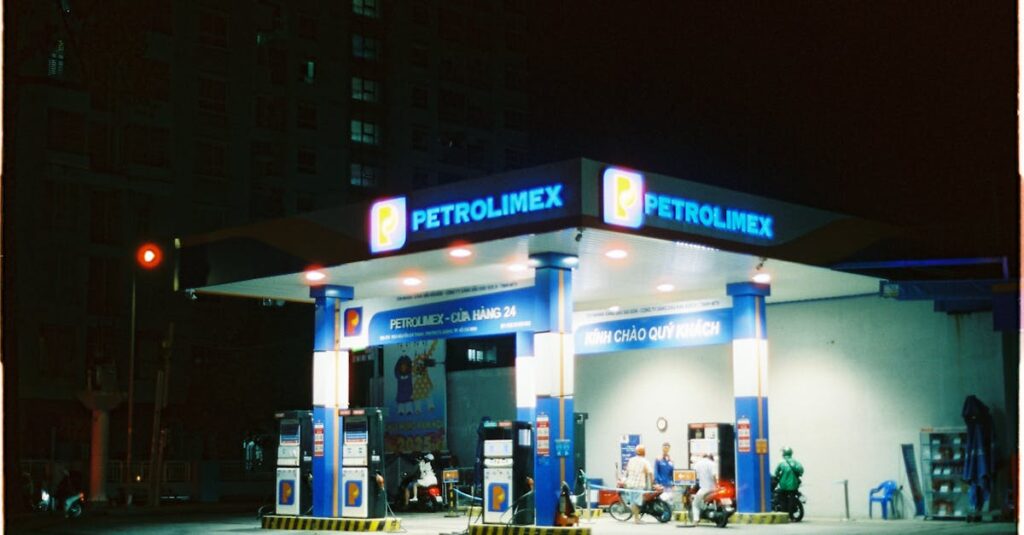 Night view of a Petrolimex gas station illuminated by neon lights with people and motorbikes.