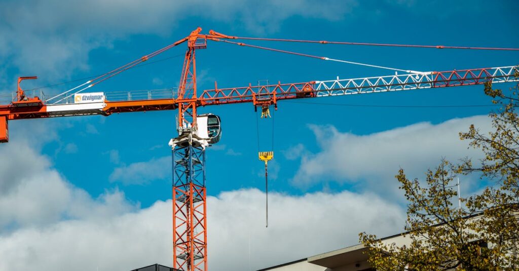 Red construction crane towering over modern building against a clear blue sky.