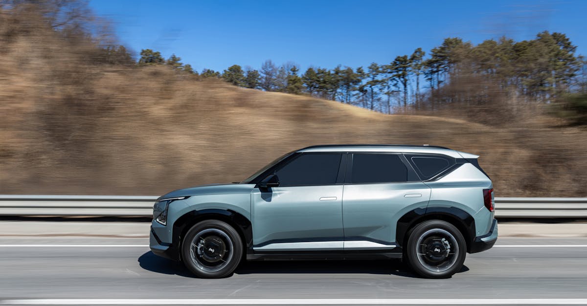 A stylish electric SUV driving on a highway with a clear blue sky and scenic background.