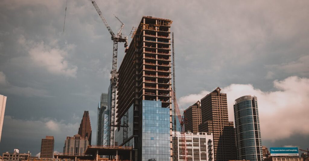 From below of contemporary multistage building exterior with hoisting cranes during construction under cloudy sky in town