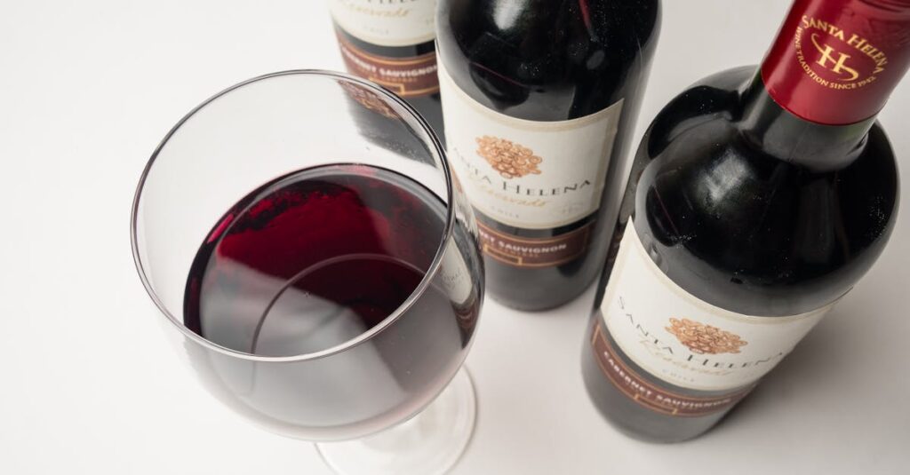 Close-up of red wine glass with Santa Helena wine bottles on a white background.