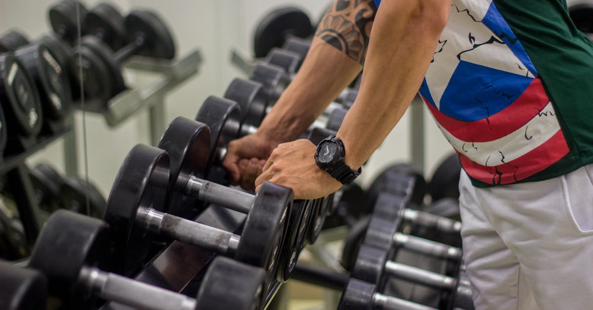 Man preparing to lift dumbbells in a gym, focusing on strength and fitness.