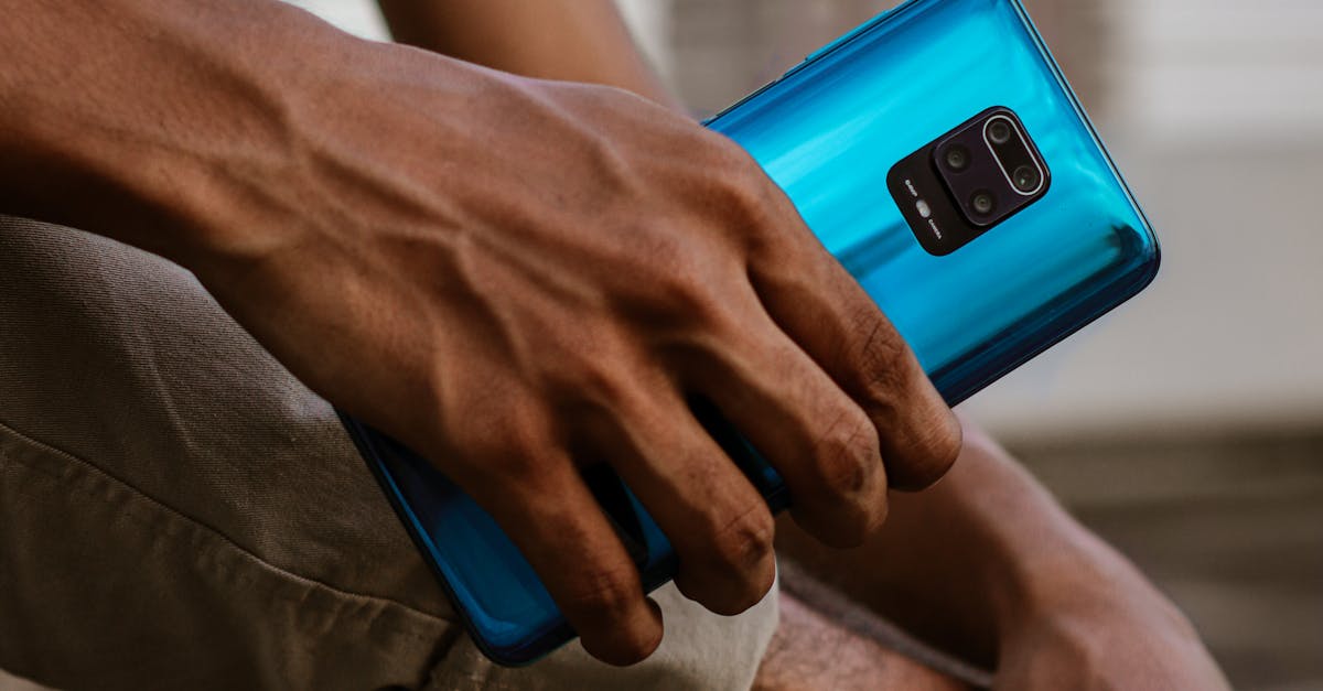 A man holds a blue smartphone outdoors, captured in Dhaka, Bangladesh.