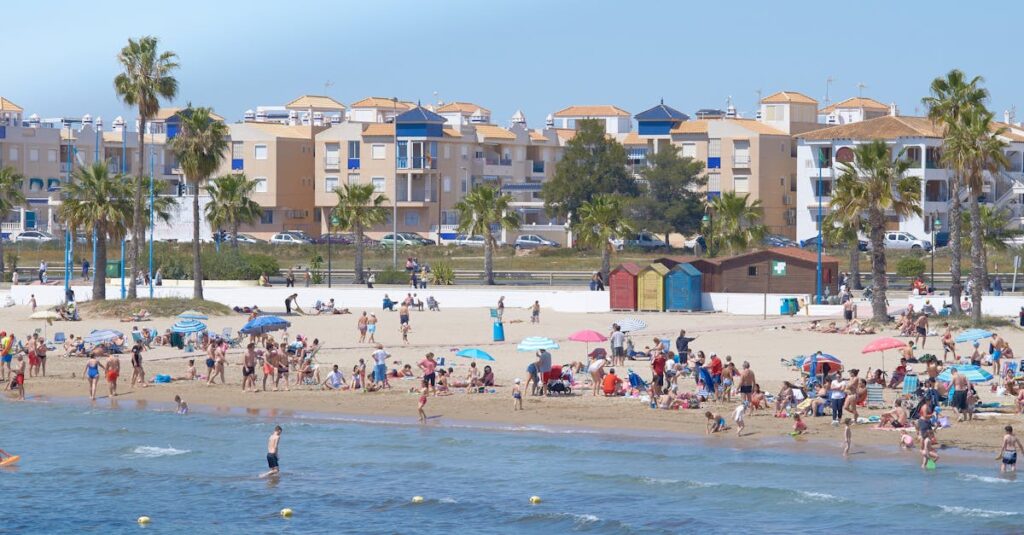 Enjoy a lively summer day at a bustling Mediterranean beach with people enjoying the sunshine.