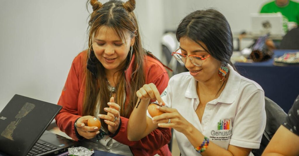 Two women decorating eggs while seated at a table, enjoying a creative crafting session.