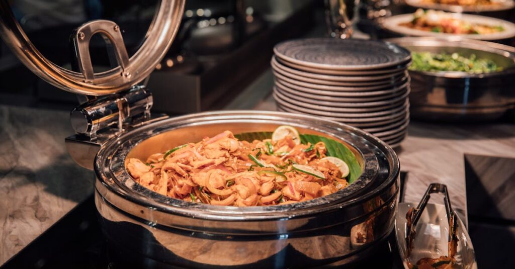 Delicious buffet style chicken curry in a chafing dish with lime and veggies.