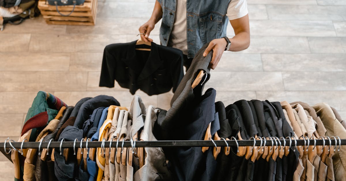 A person holds a jacket while organizing clothes on a rack in a stylish boutique.